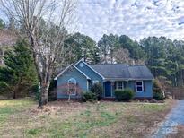 Ranch style home with gray siding, dark door, and landscaping at 213 Meadow Wind Ct, Monroe, NC 28110