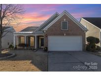 Brick ranch home with attached garage and landscaped lawn at 10318 Threatt Woods Dr, Charlotte, NC 28277