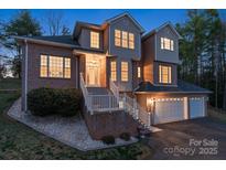 Inviting two-story brick home featuring a two-car garage and well-lit entrance at dusk at 5774 Crown Ter, Hickory, NC 28601