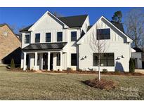 New construction two-story home with white siding, black accents, and a well-manicured lawn at 8823 Wingard Rd, Waxhaw, NC 28173