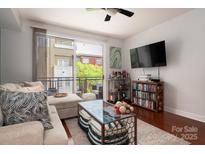 Bright living room with comfy sectional sofa, balcony access, and hardwood floors at 1315 East Blvd # 420, Charlotte, NC 28203