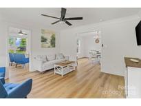 Bright living room with light hardwood floors and a neutral color palette open to the dining area at 2328 Sanders Ave, Charlotte, NC 28216