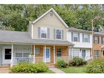 Brick front townhouse with a charming porch and well-maintained landscaping at 6325 Windsor Gate Ln, Charlotte, NC 28215