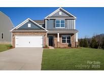 Two-story house with stone and gray siding, two-car garage, and landscaped lawn at 10610 Tuff Ln, Davidson, NC 28036