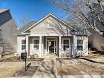 Beige house with front porch, rocking chairs, and landscaping at 11127 Aprilia Ln, Cornelius, NC 28031