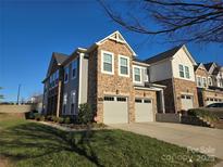 Modern two-story townhome with stone and siding accents, two-car garage, and landscaped lawn at 5860 Clan Maclaine Dr, Charlotte, NC 28278