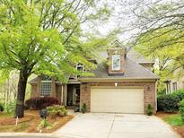 Charming brick home featuring a two-car garage, manicured lawn, and mature trees providing ample shade at 10607 Newberry Park Ln, Charlotte, NC 28277