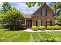 Charming red brick home featuring a beautifully landscaped front yard and classic black shutters at 254 Streamside Pl, Mooresville, NC 28115