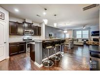 Open kitchen with dark cabinetry, granite countertops, stainless appliances and breakfast bar with pendant lighting at 3033 Honeylocust Ln, Fort Mill, SC 29707