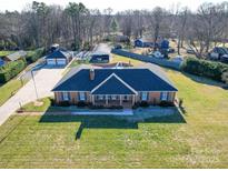 Expansive brick home featuring an in-ground pool, detached garage, and lush green lawn at 7169 Pleasant Grove Rd, Charlotte, NC 28216