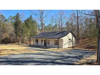 Charming home with a gravel driveway, featuring a black roof and a covered front porch at 107 Skyland Dr, Mount Gilead, NC 27306