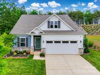 Charming home boasts a well-manicured lawn and inviting two-car garage, complemented by beautiful stone accents at 15298 Windward Ln, Lancaster, SC 29720