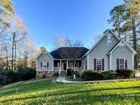 Ranch style home with gray siding, red shutters, and a landscaped lawn at 2923 Meadow Creek Ln, Monroe, NC 28110