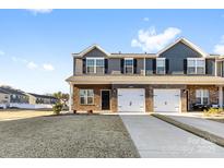 Two-story townhome with brick and gray siding, two-car garage, and landscaped lawn at 543 San Marco Dr # 16, Gastonia, NC 28056