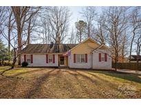 Ranch style home with white brick and yellow siding, red shutters, and American flag at 714 Mattingwood Dr, Charlotte, NC 28270