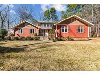 Ranch style home with red siding, mature landscaping, and a spacious yard at 3406 Red Fox Trl, Weddington, NC 28104