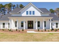 White farmhouse exterior with a wraparound porch and landscaping at 0000 Trull Hinson Rd, Wingate, NC 28174