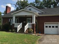 Brick ranch home with attached garage, front porch, and landscaped lawn at 1250 Wendover Ave, Albemarle, NC 28001