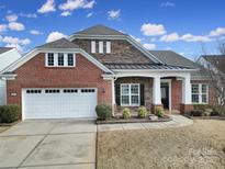 Brick front elevation of charming two-story home with a metal roof and landscaping at 4047 Blackburn Ct, Fort Mill, SC 29707