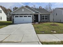 Newly built home with stone and siding accents, two-car garage, and landscaped lawn at 171 Wembury Ln, Troutman, NC 28166