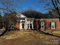 Brick ranch house with a landscaped lawn and mature trees at 13407 Stephendale Dr, Charlotte, NC 28273