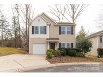 Tan two-story house with a white garage door and landscaping at 1444 Swaying Branch Ln, Clover, SC 29710