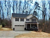 Charming two-story home with a welcoming front porch and attached two-car garage, set in a serene wooded location at 5528 Brickstone Dr, Charlotte, NC 28227