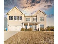 Two-story house with beige siding, a large front yard, and a two-car garage at 10045 Carousel Corral Dr, Midland, NC 28107