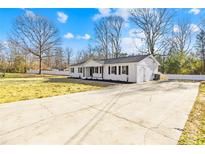 Charming single-story home featuring a white brick exterior, black shutters, and an expansive front yard at 1006 Woodside Dr, Kings Mountain, NC 28086