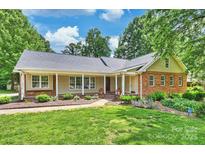 Charming ranch-style home featuring a welcoming front porch, lush lawn, and manicured landscaping at 7135 Folger Dr, Charlotte, NC 28270