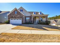 Two-story house with stone and siding exterior, two-car garage, and manicured lawn at 900 Raffaelo Vw, Mount Holly, NC 28120