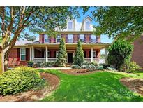 Charming brick two-story home featuring a welcoming front porch and beautifully landscaped front yard at 103 Glenholden Ln, Mooresville, NC 28115