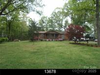 Ranch home with covered porch, surrounded by lush landscaping and mature trees at 3987 Nc 182 Hwy, Lincolnton, NC 28092