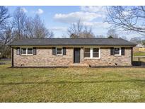 Brick ranch house with a landscaped lawn and dark-colored front door at 4804 Chapel Grove Rd, Gastonia, NC 28052