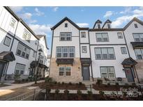 Modern three-story townhome with gray and white exterior, brick accents, and a charming front porch at 6027 Towering Oaks Dr, Charlotte, NC 28205