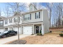 Two-story townhome with gray siding, stone accents, and a two-car garage at 7216 Somerford Rd, Charlotte, NC 28215