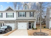 Two-story townhome with gray siding, stone accents, and a two-car garage at 7216 Somerford Rd, Charlotte, NC 28215