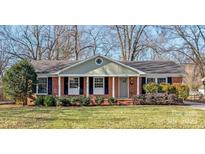 Brick ranch house with a well-maintained lawn and mature trees at 941 Squirrel Hill Rd, Charlotte, NC 28213