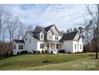 Two story home with white brick and taupe accents, front porch, and landscaped yard at 2010 Belle Grove Dr, Marvin, NC 28173