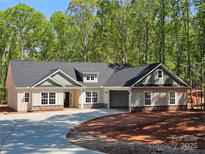Charming single story home with neutral siding, stone accents, attached garage and wooded backdrop at 609 Shiloh Unity Rd, Lancaster, SC 29720