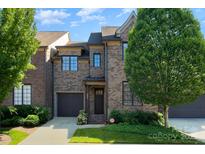 Charming brick townhome featuring an attached garage and manicured front lawn at 6411 Aldworth Ln, Charlotte, NC 28226