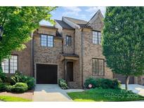 Charming brick townhouse featuring an attached garage, manicured lawn, and well-maintained landscaping at 6411 Aldworth Ln, Charlotte, NC 28226