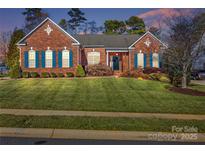 Brick ranch home with landscaped lawn and blue shutters at 1117 Butterburr Dr, Matthews, NC 28104