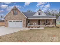 Charming brick home featuring a covered porch, attached two-car garage, and a well-manicured lawn at 1076 Furnace Rd, Iron Station, NC 28080