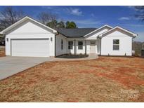 Charming single-story home featuring white siding, attached garage, and a well-maintained lawn at 1112 Wiscassett St, Albemarle, NC 28001