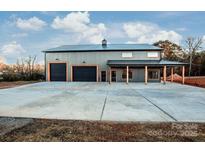 Gray metal barn-style home with triple garage doors and covered porch at 219 Mock Mill Rd, Statesville, NC 28677