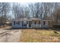 Newly renovated ranch home featuring a gray exterior, white porch, and landscaped yard at 4700 Hartland Cir, Charlotte, NC 28205