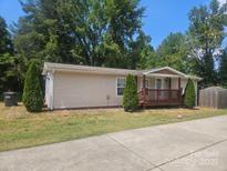 Tan mobile home with a small front porch and landscaping at 5024 Victoria Ave, Charlotte, NC 28269