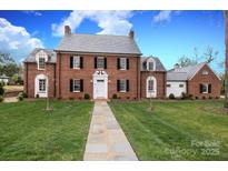 Charming brick home featuring a manicured lawn, stone walkway, and classic architectural details at 2400 Mecklenburg Ave, Charlotte, NC 28205