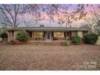 Charming single-story brick home with a cozy front porch and mature trees under a colorful sky at 3050 Wilkesboro Hwy, Statesville, NC 28625